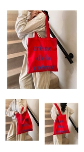 Détail du sac fourre-tout en toile rouge avec imprimé crème de la crème porté par un mannequin