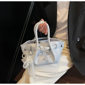 Detail of white pleated bucket bag with pearl heart charm and lace accent