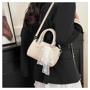 Detail of cream Boston bag with fine weave texture, lace streamers and pearl charms