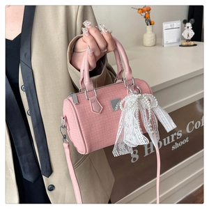 Detail of pink tweed boston bag with elegant lace bow and pearl pendant accessory