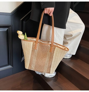 Straw tote bag detail with contrast color weave and leather shoulder straps shown on stairs