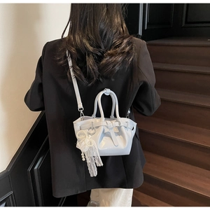 Detail of light blue pleated bucket bag with lace bow and pearl pendant charm