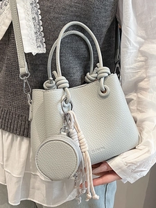 Chic grey litchi grain bucket bag with round handles and tassel detail for daily commute
