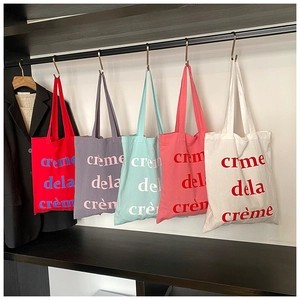 Détail de cinq sacs cabas en toile de différentes couleurs avec imprimé crème dela crème