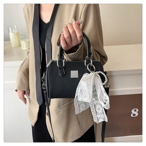 Detail of black Boston bag with silver hardware, pearl charm, and textured finish