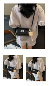 Detail of minimalist black pillow bag featuring silver twist lock and cute bear charm pendant