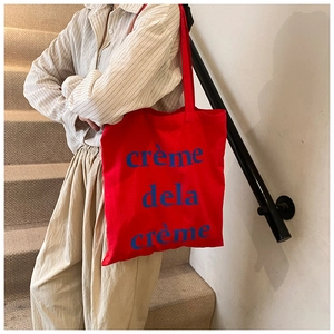 Détail du sac cabas en toile rouge avec imprimé bleu crème de la crème et bandoulière assortie