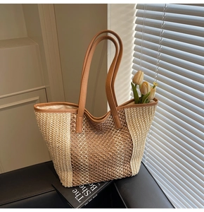 Close-up of woven straw tote bag with contrast leather handles on a black leather chair