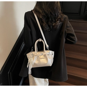 Detail of cream pleated bucket bag with pearl lace charm and crossbody strap