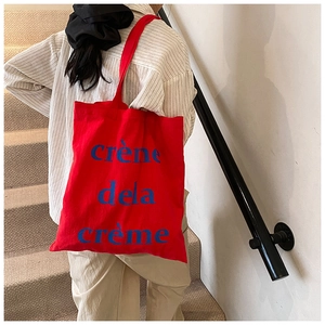 Détail du sac fourre-tout en toile rouge avec texte bleu sur un fond d'escalier