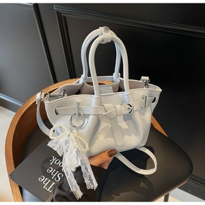 Detail view of light blue pleated bucket bag with pearl lace bow on a vintage chair