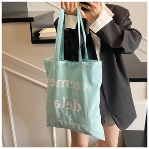 Détail du sac cabas en toile bleu clair avec typographie crème de la crème artistique