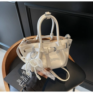 Close-up of beige pleated bucket bag with pearl lace bow charm and premium PU leather texture