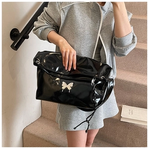 Détail du sac cabas en cuir noir brillant avec boucle papillon argentée et cordons