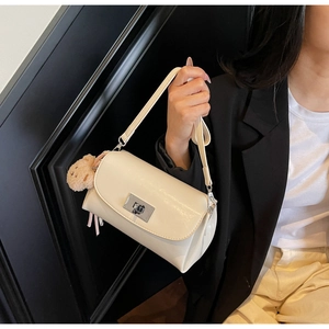 Detail of cream flap shoulder bag featuring a silver twist lock and plush bear charm