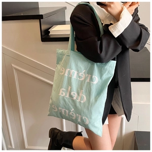 Détail du sac cabas en toile vert menthe avec imprimé artistique creme dela creme à l'épaule