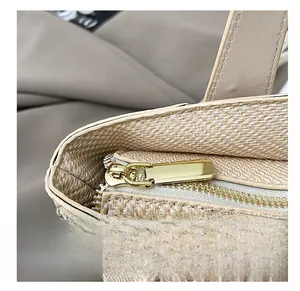 Detail shot of smooth golden zipper and texture on a beige straw woven handbag