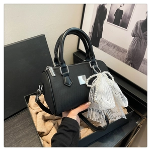 Detail of black woven Boston bag with pearl lace charm and silver brand plaque