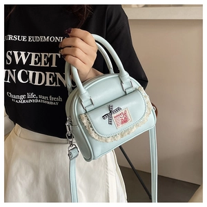 Close-up of light blue Boston bag featuring lace trim, bow, and rabbit patch detail