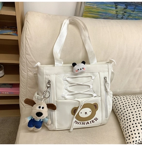 Détail du sac cabas en toile blanche avec rubans quadrillés et broderie d'ours