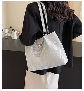 Detailed view of silver wave texture tote bag with metallic butterfly charm on a model
