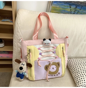 Détail d'un sac cabas coloré avec motif ours et pendentif chien en peluche sur canapé