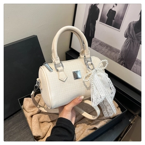 Detail of Boston bag featuring ivory woven fabric with lace pearl bow and metal plaque