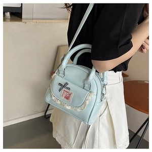 Detail view of light blue Boston bag with white lace trim and checkered bow accent