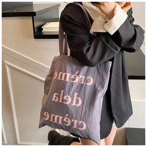 Détail d'un sac cabas en toile violette avec texte crème de la crème rose pour femme