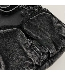 Detailed close-up of dark denim fabric with frayed edges and multi-pocket zipper design