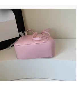 Detailed close-up of a pink patent leather underarm bag with pearl handle and lace ribbons