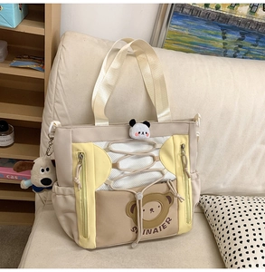 Détail du sac cabas en toile avec touches jaunes, poche filet et breloques mignonnes