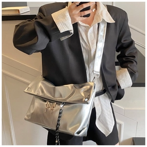 Vue détaillée du sac argenté métallisé avec boucle papillon chromée et bandoulière large