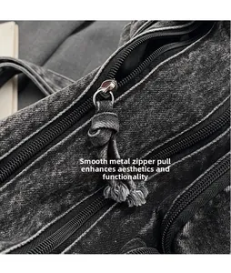Detailed close-up of smooth circular metal zipper puller on washed denim tote bag