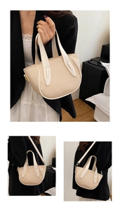 Detailed view of beige straw bucket bag featuring white leather trim and metal hardware