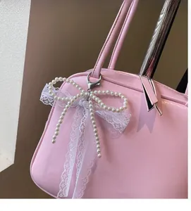 Detailed shot of pink leather bag with elegant pearl lace bow pendant and silver clasp