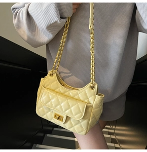Detail shot of a yellow quilted crossbody bag with a metal twist lock and chain strap