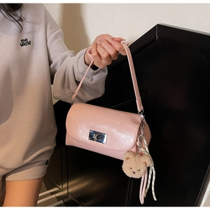 Detail of pink faux leather bag with silver metal lock and cute plush bear charm