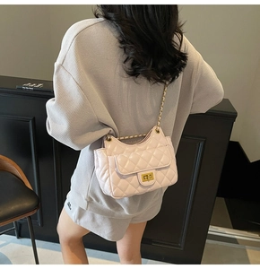 Pink quilted shoulder bag with gold chain strap shown worn by model in a stylish setting