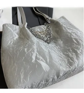 Detail of silver tote bag featuring crinkled metallic fabric and silver butterfly chain