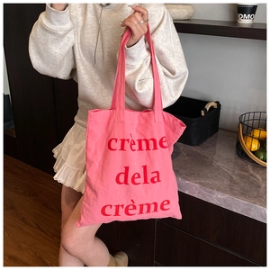 Détail du sac fourre-tout en toile rose avec texte rouge crème dela crème en décor