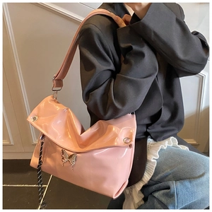 Détail d'un sac hobo rose brillant avec breloque papillon et bandoulière réglable