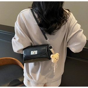 Detail view of black oil wax leather crossbody bag with silver lock and bear pendant