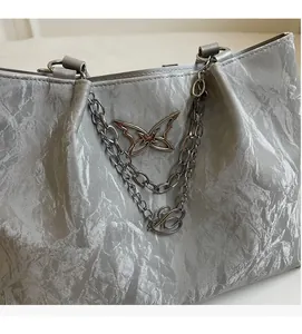 Detailed close-up of metallic silver tote bag fabric with silver butterfly pendant detail