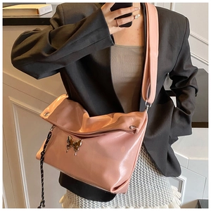 Détail d'un sac cabas rose en cuir souple brillant avec un ornement papillon doré