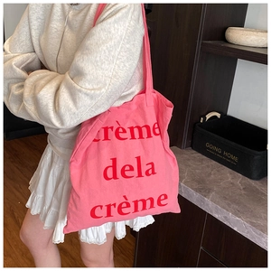 Détail du sac cabas en toile rose avec inscription en texte français rouge sur l'épaule