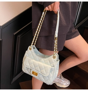 Close-up of mint green quilted shoulder bag with gold chain strap on a model