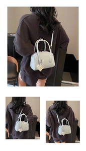 Close-up of light blue leather handbag with pearl heart charm and crossbody strap