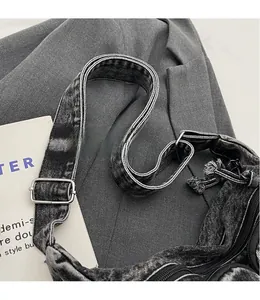 Close-up of adjustable denim shoulder strap with silver buckle and smooth zipper