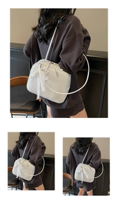 Detail of light gray pillow bag featuring white lace bow and elegant pearl chain ornament
